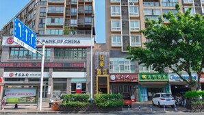 Un edificio de varios pisos con un letrero de 'Bank of China', un letrero de 'Hotel' y varias tiendas, incluyendo una farmacia y un restaurante.