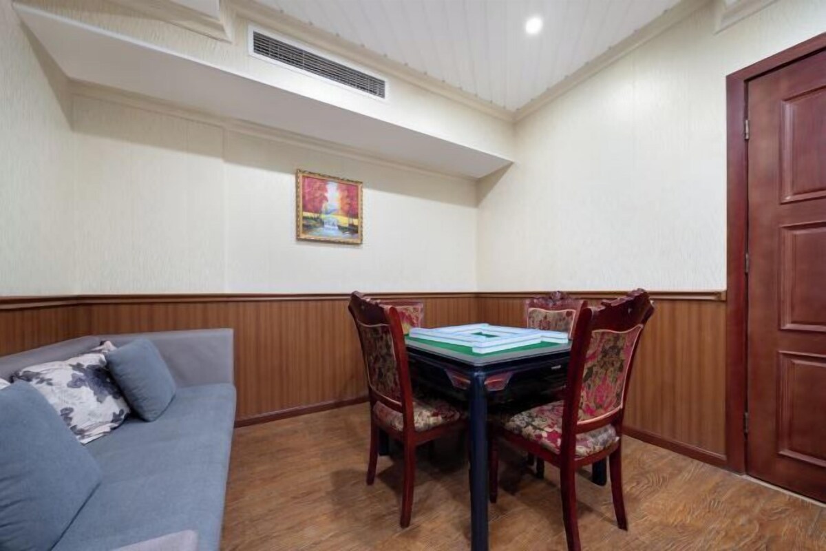 A dining area with a table and chairs, a sofa, a wooden door, and a ceiling vent.