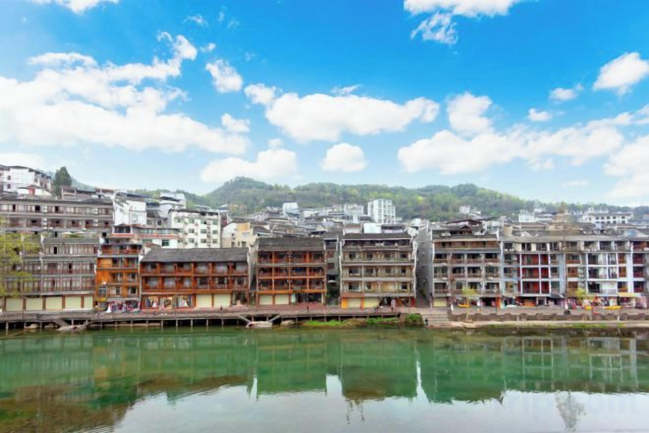 Vista del río con edificios tradicionales de varios pisos, reflejándose en el agua.