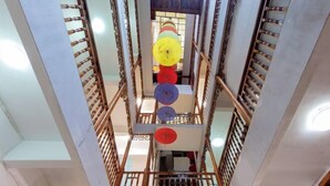Un interno a più livelli con una scala centrale circondata da ringhiere in legno e una serie di oggetti circolari colorati al piano superiore.