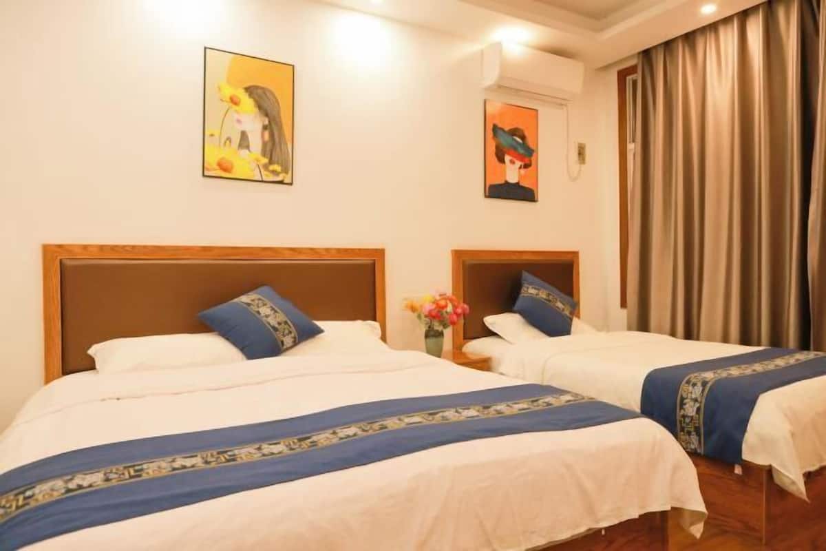 A hotel room with two beds, a wooden headboard, a painting on the wall, and a curtain.