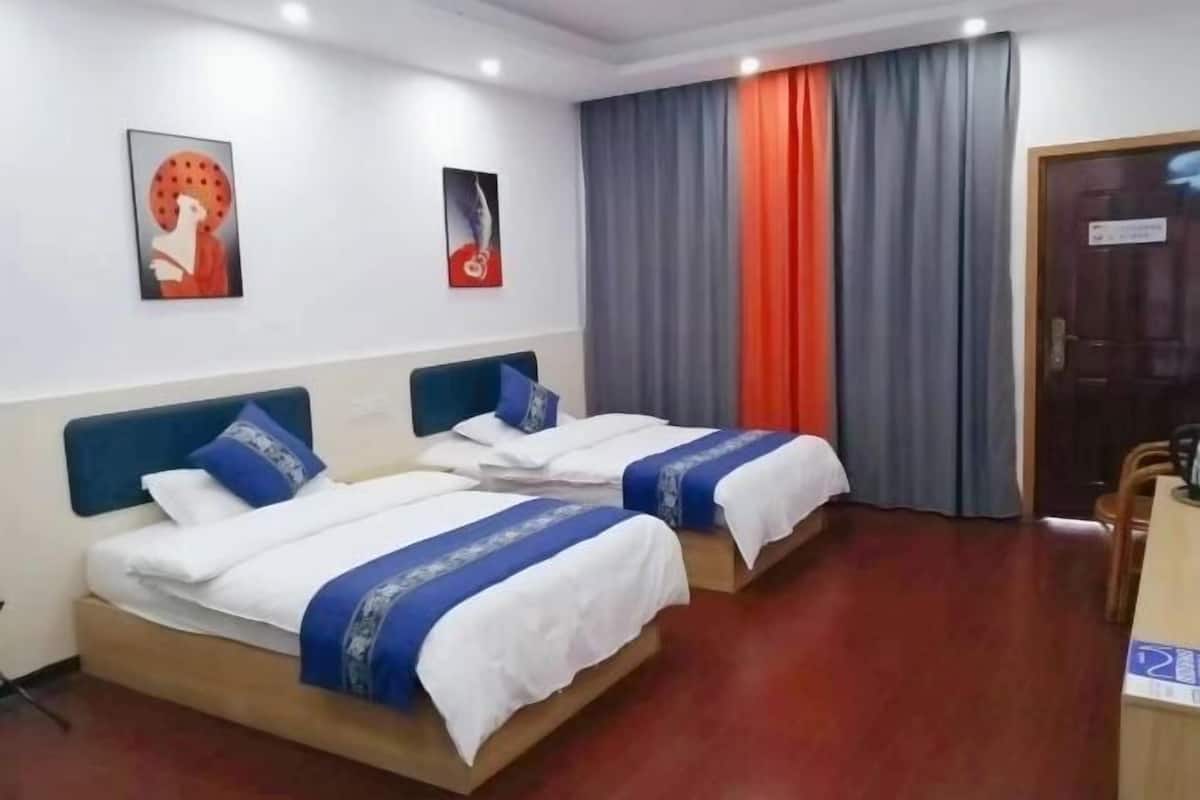 A hotel room with two beds, a desk, and a chair.