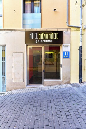 Entrada de un hotel con un letrero que dice 'Hotel Barrio Húmedo' y un letrero azul de accesibilidad para personas con discapacidad.
