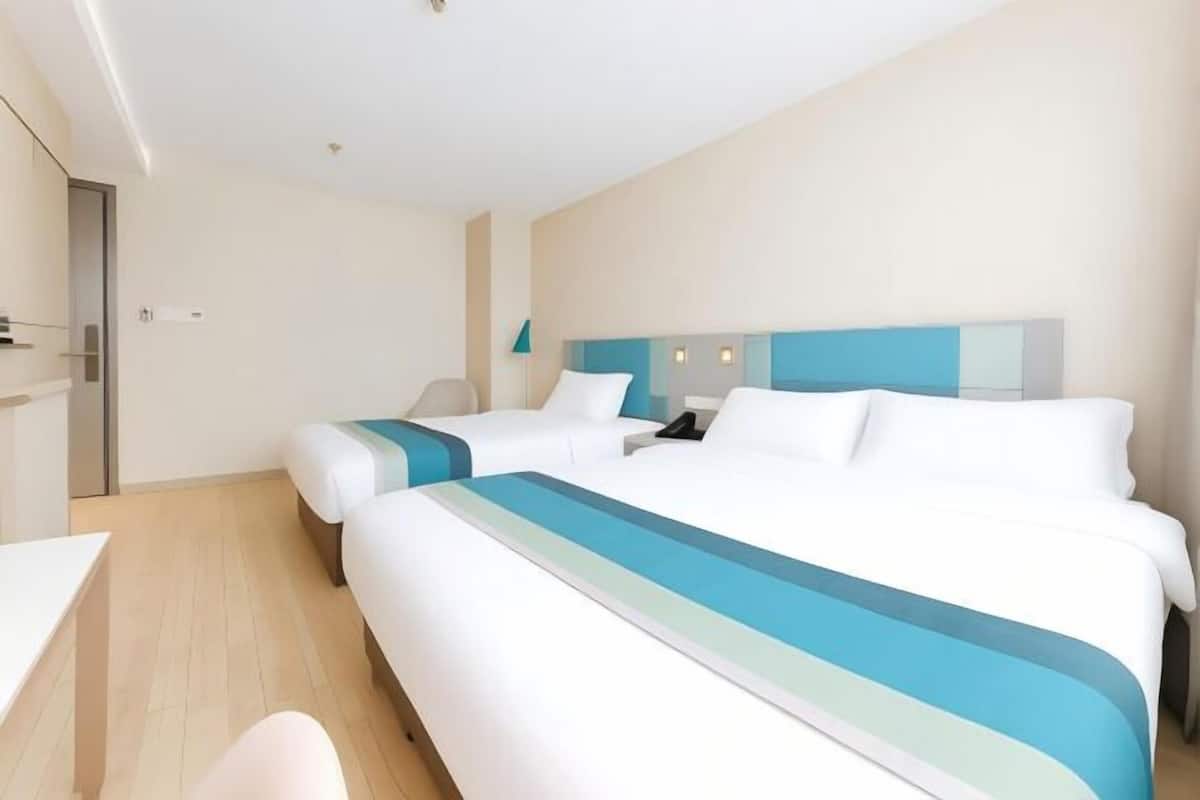 Una camera d'albergo con due letti, una scrivania e una sedia.