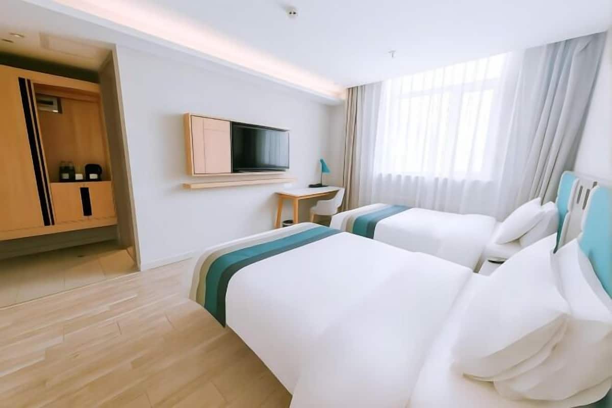 Camera d'albergo con due letti, una TV, una scrivania e un armadio.