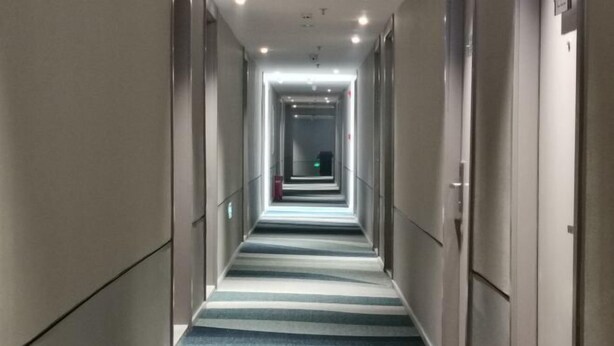 A long, narrow hotel corridor with a striped carpet and doors on both sides. - Home Inn Business Hotel (Benxi Railway Station Branch) (Benxi)