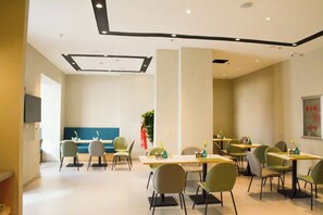 Un comedor moderno con mesas y sillas, una recepción y una planta grande.