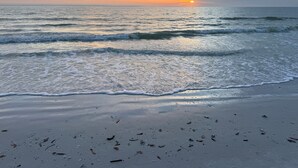 A beach with waves and a sunset.