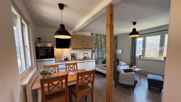 Una cocina moderna con armarios de madera, una mesa de comedor con sillas y luces colgantes.