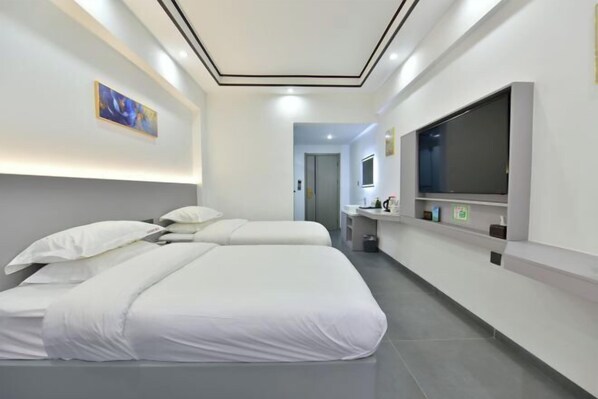 Een moderne hotelkamer met twee bedden, een grote flatscreen televisie, een kleine badkamer en een schilderij aan de muur.