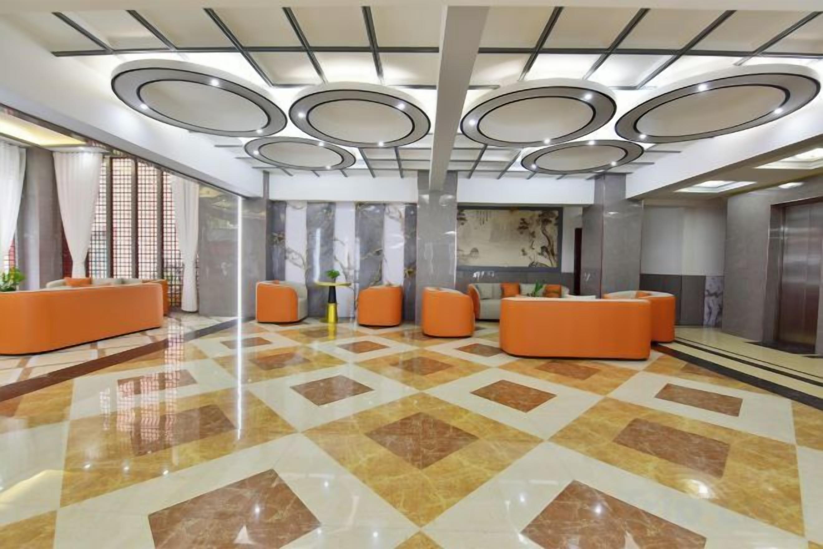 A hotel lobby with a check-in counter, seating area, and a large mirror.