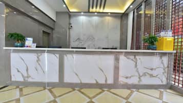 A reception area with marble counters, a check-in desk, and a patterned floor.