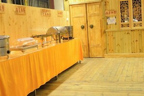 A buffet table with food containers, a wooden door, and a traditional Chinese window. - Wangfu Hot Spring Hotel (Jinghong)