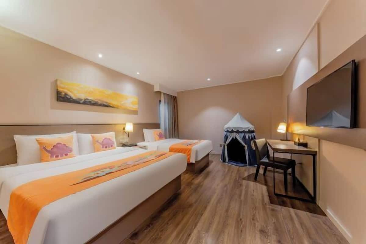 A hotel room with two beds, a small desk, a chair, a tent-like structure, and a painting on the wall.