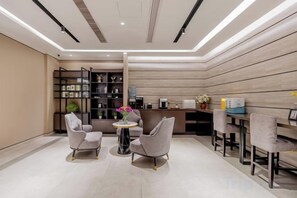A modern interior with a reception desk, seating area, and a coffee station. - Homeinn Plus Hotel (Hangzhou Sijiqing Qianjiang New Town Shuangling Road) (Hangzhou)