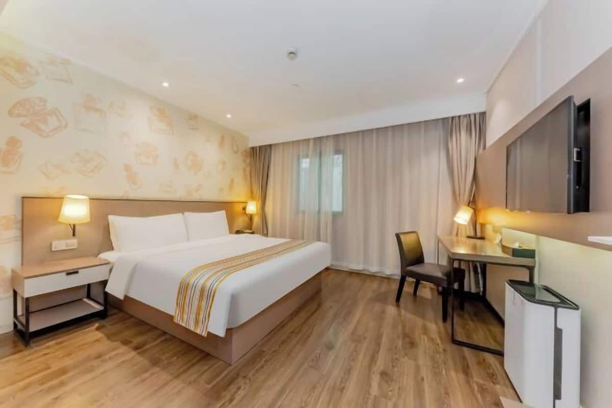 A hotel room with a large bed, bedside tables with lamps, a desk with a chair, and a television.