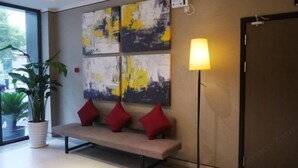 Un vestíbulo moderno con un banco, una lámpara de pie y arte abstracto en la pared.