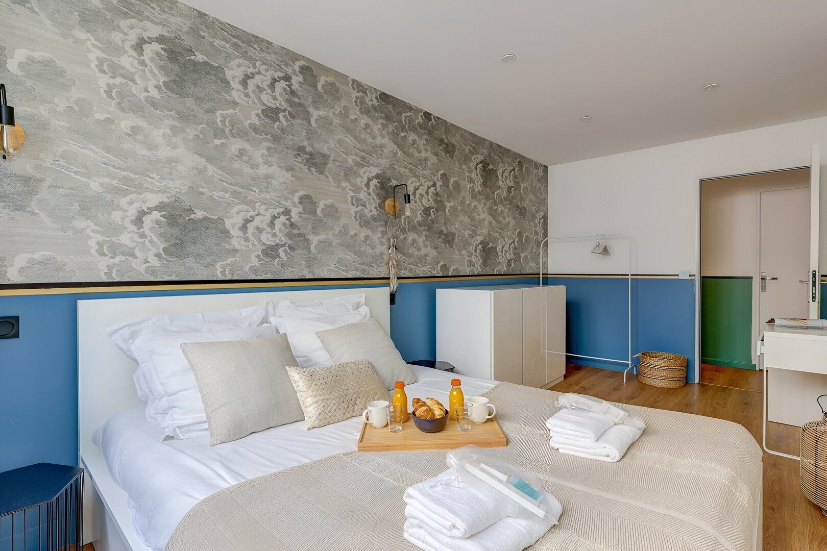 A modern hotel room with a large bed, a breakfast tray, and a view of the city.