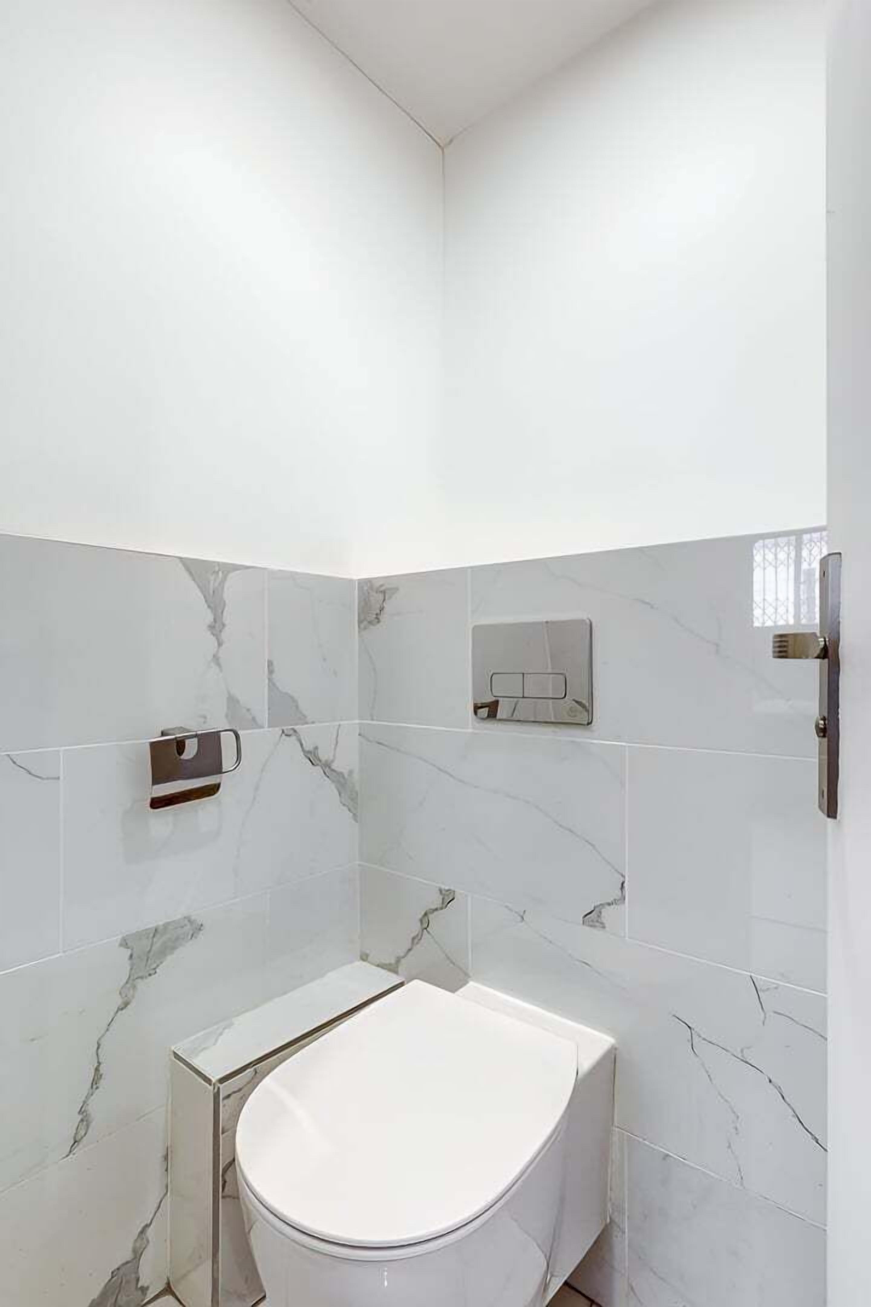 Ein modernes Badezimmer mit Toilette, Handtuchhalter und Wandseifenspender.