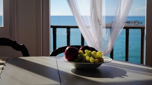 A table with a bowl of fruit and a view of the sea through sheer curtains. - In front of the sea in Sitges (sitges)
