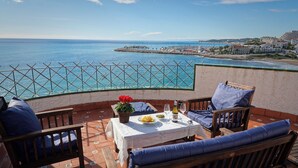 An outdoor terrace with a table set for two, overlooking a coastal view. - In front of the sea in Sitges (sitges)