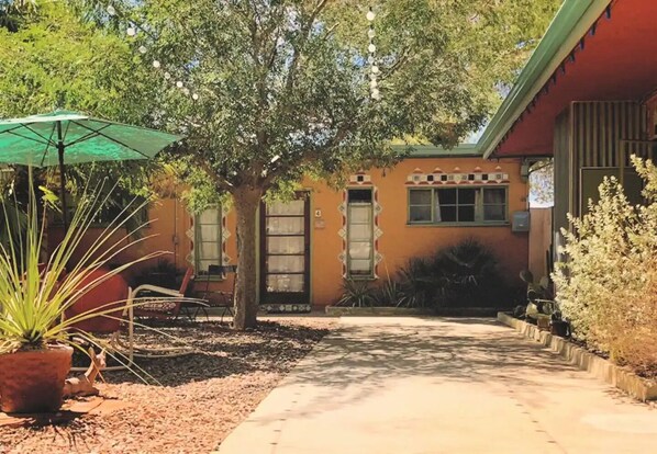 A building with a green awning, a tree in front, and a pathway leading to the entrance. - Suite 4 - The Western Nomad (Joshua Tree)
