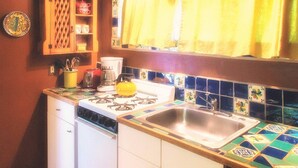 A compact kitchen with a gas stove, a sink, and a coffee maker.
