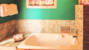 A bathroom with a bathtub, a towel rack, and a window with curtains.