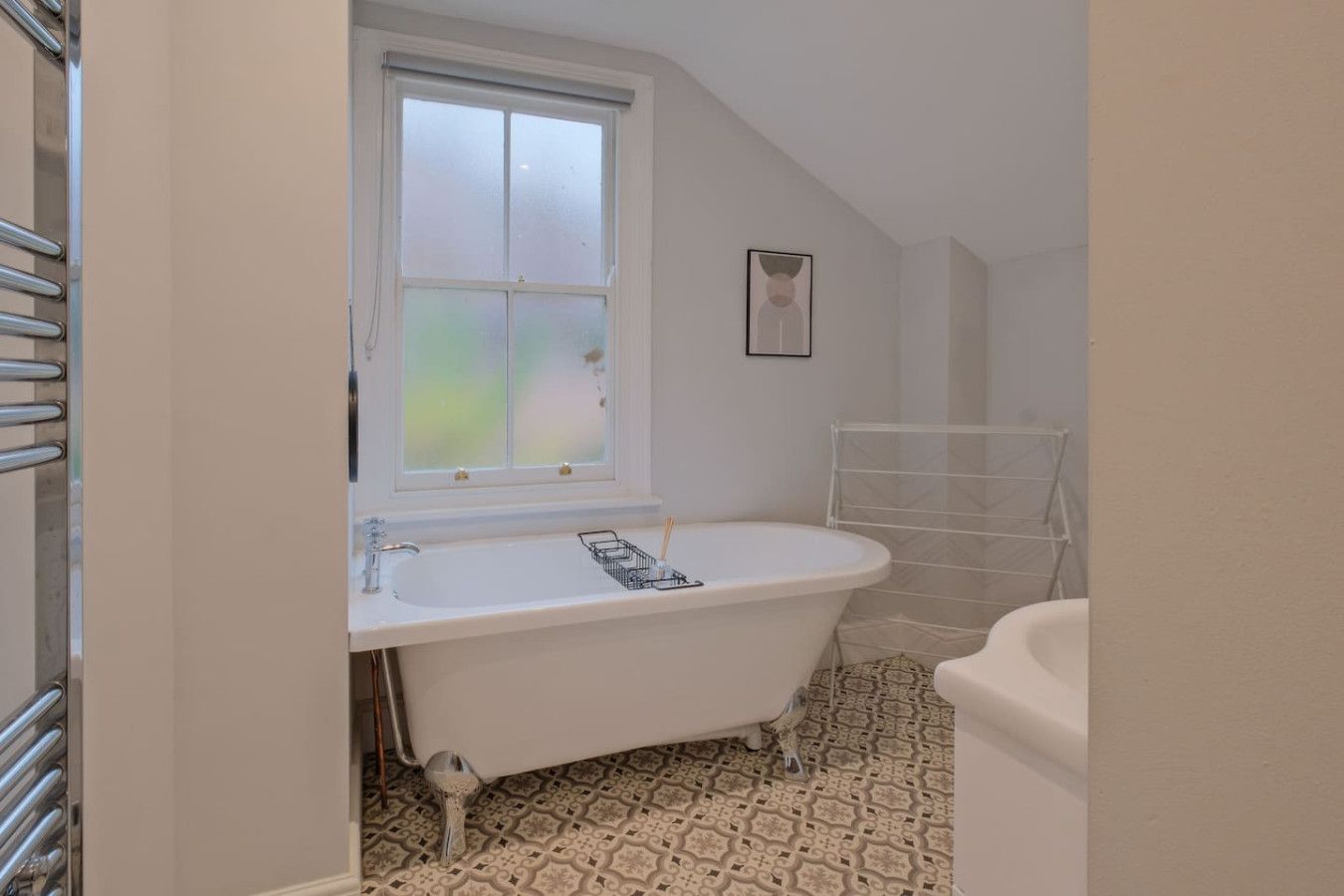 Ein Badezimmer mit einer freistehenden Badewanne, einem Fenster und einem Handtuchhalter.