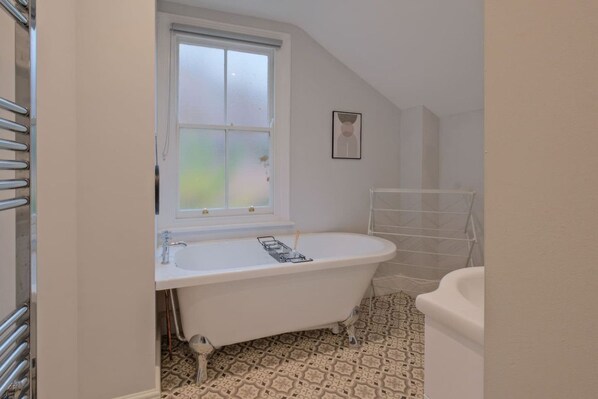 A bathroom with a freestanding bathtub, a window, and a towel rack.