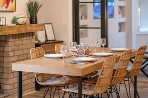 A dining area with a wooden table set for four, surrounded by wicker chairs.