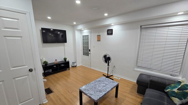 A living room with a flat-screen TV, a standing fan, a patterned coffee table, a sofa, and a window with blinds. - Clean precious house (Ajax)