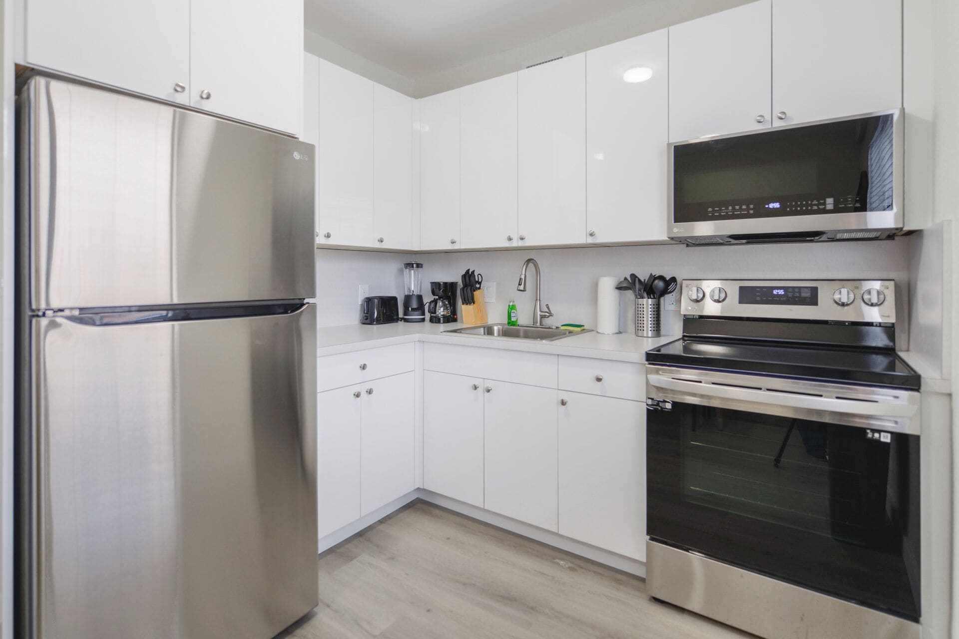 A modern kitchen with stainless steel appliances, white cabinetry, and a built-in microwave.