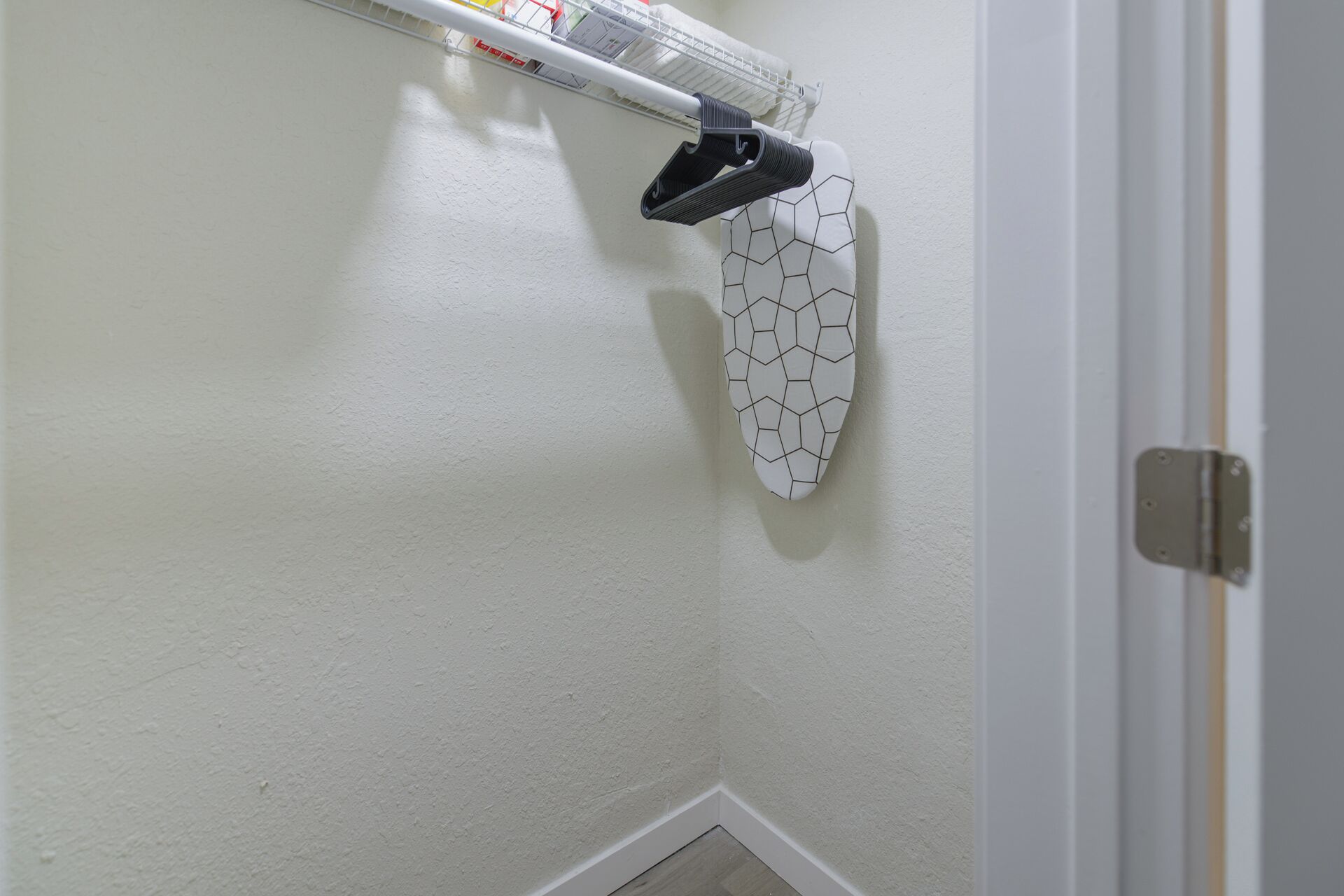 A corner of a room with a white textured wall, a white door frame, and a white door.