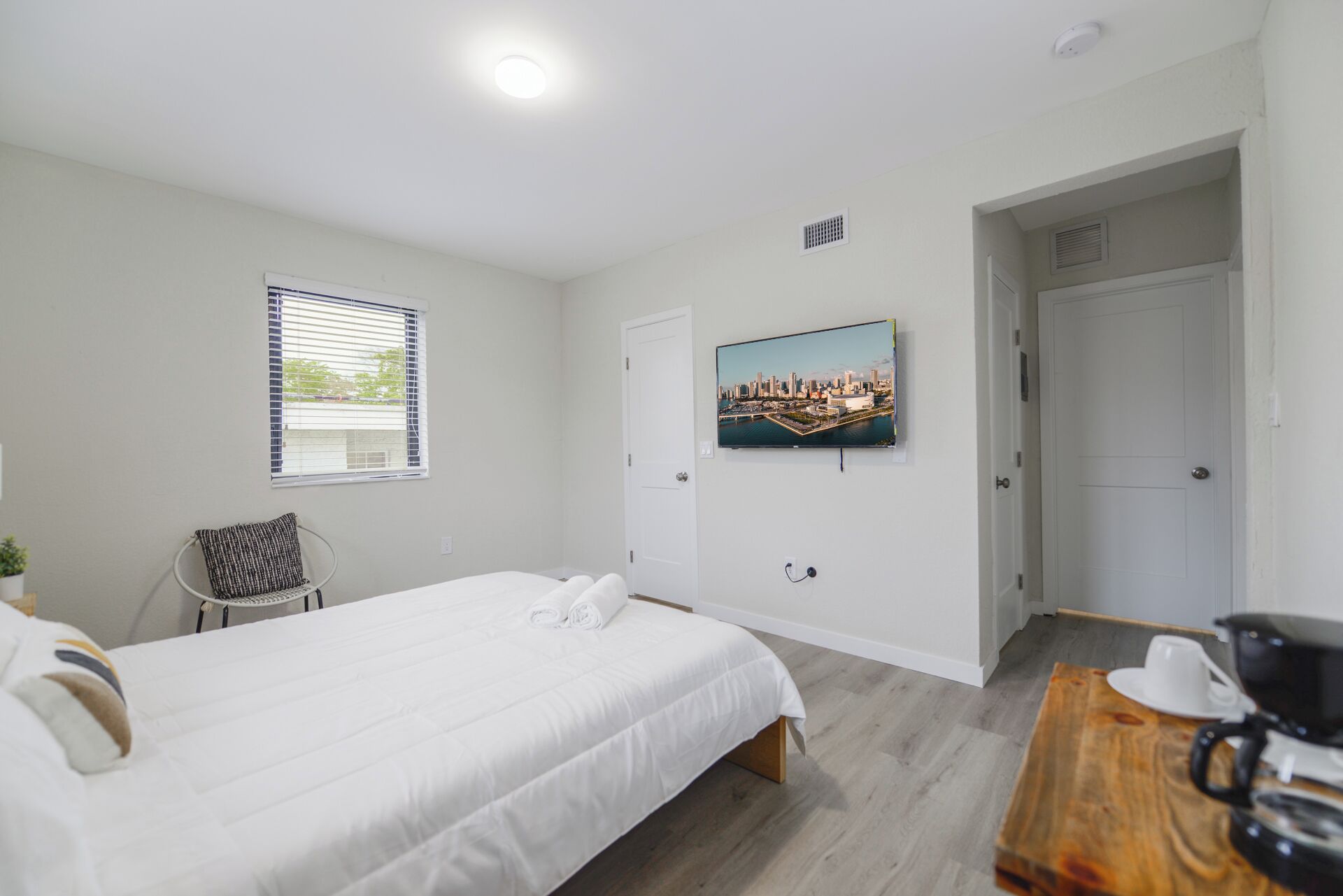 Une chambre d’hôtel avec un lit, une chaise, une table basse et un téléviseur diffusant une vue sur la ville.
