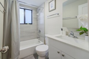 A modern bathroom with a bathtub, toilet, and sink. - Stylish Apartments on Iconic Calle Ocho (Miami)