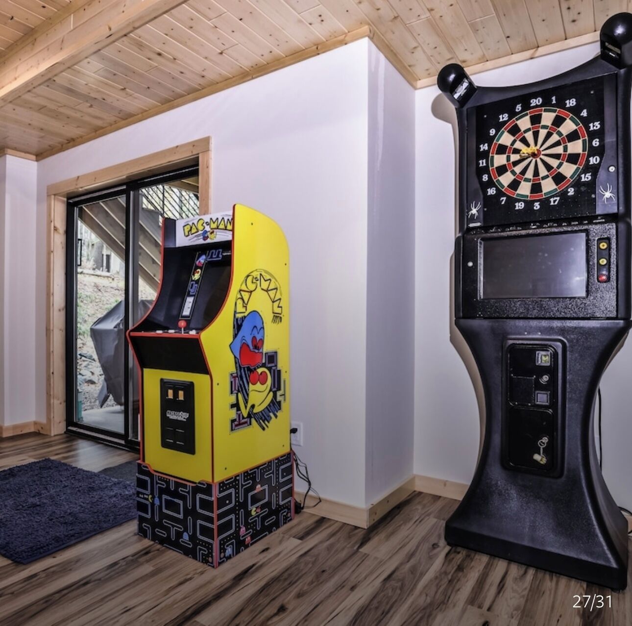 Une pièce avec une borne d’arcade Pac-Man et un jeu de fléchettes.