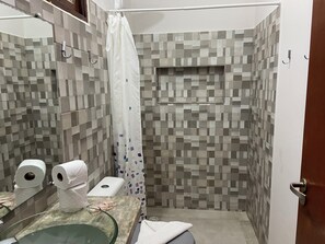A bathroom with a shower, tiled walls, a glass sink, and a toilet. - Valnete Brancalion Weiss-Epp (São Sebastião)