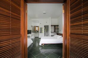 A hotel room with a bed, a desk, and a kitchenette. - Valnete Brancalion Weiss-Epp (São Sebastião)
