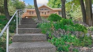 Una casa con una escalera de piedra que lleva a una terraza de madera rodeada de árboles.