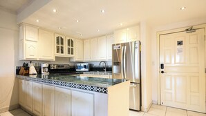 Una cocina moderna con armarios blancos, un refrigerador de acero inoxidable y un salpicadero de azulejos.