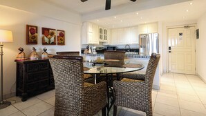 Una cocina moderna con armarios blancos, un comedor con sillas estampadas y un ventilador de techo.