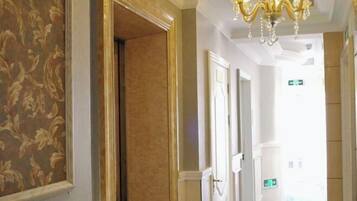 A hallway with patterned wallpaper, a chandelier, and doors leading to other rooms.