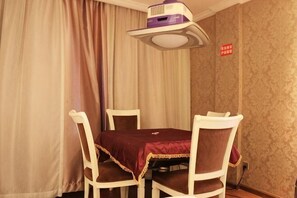 Un área de comedor con una mesa y cuatro sillas, un proyector y una cortina.