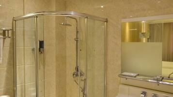 Cabina de ducha con paredes de vidrio, cabezal de ducha de mano y grifo empotrado.