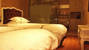 Une chambre d’hôtel avec un grand lit, une douche en verre et une kitchenette.