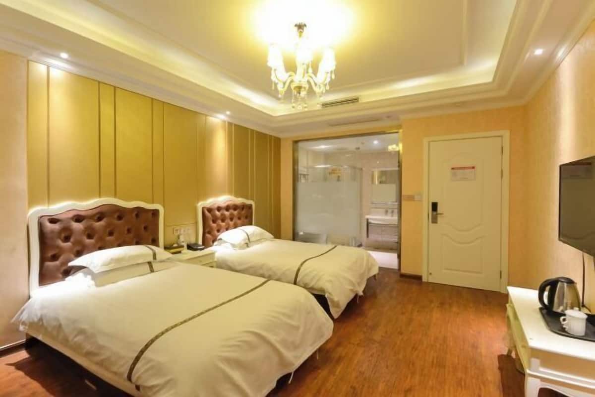 Hotellihuone, jossa on kaksi sänkyä, televisio ja työpöytä sekä vedenkeitin.