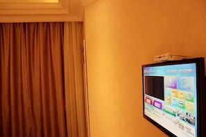Un téléviseur fixé au mur, avec une télécommande posée sur le dessus.