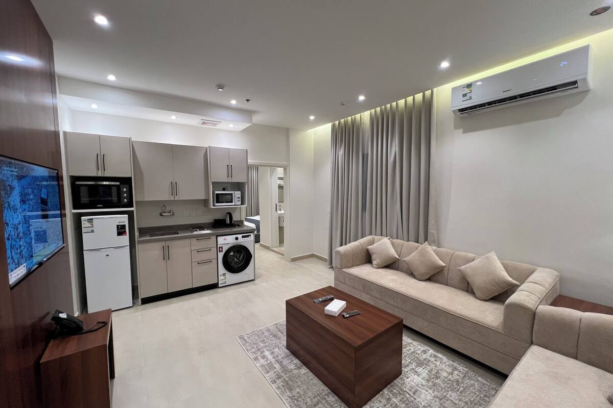A modern living room with a beige sofa, a coffee table, and a TV mounted on the wall.