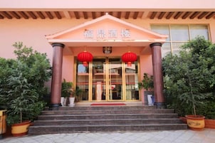 A building entrance with a sign, steps, and potted plants.